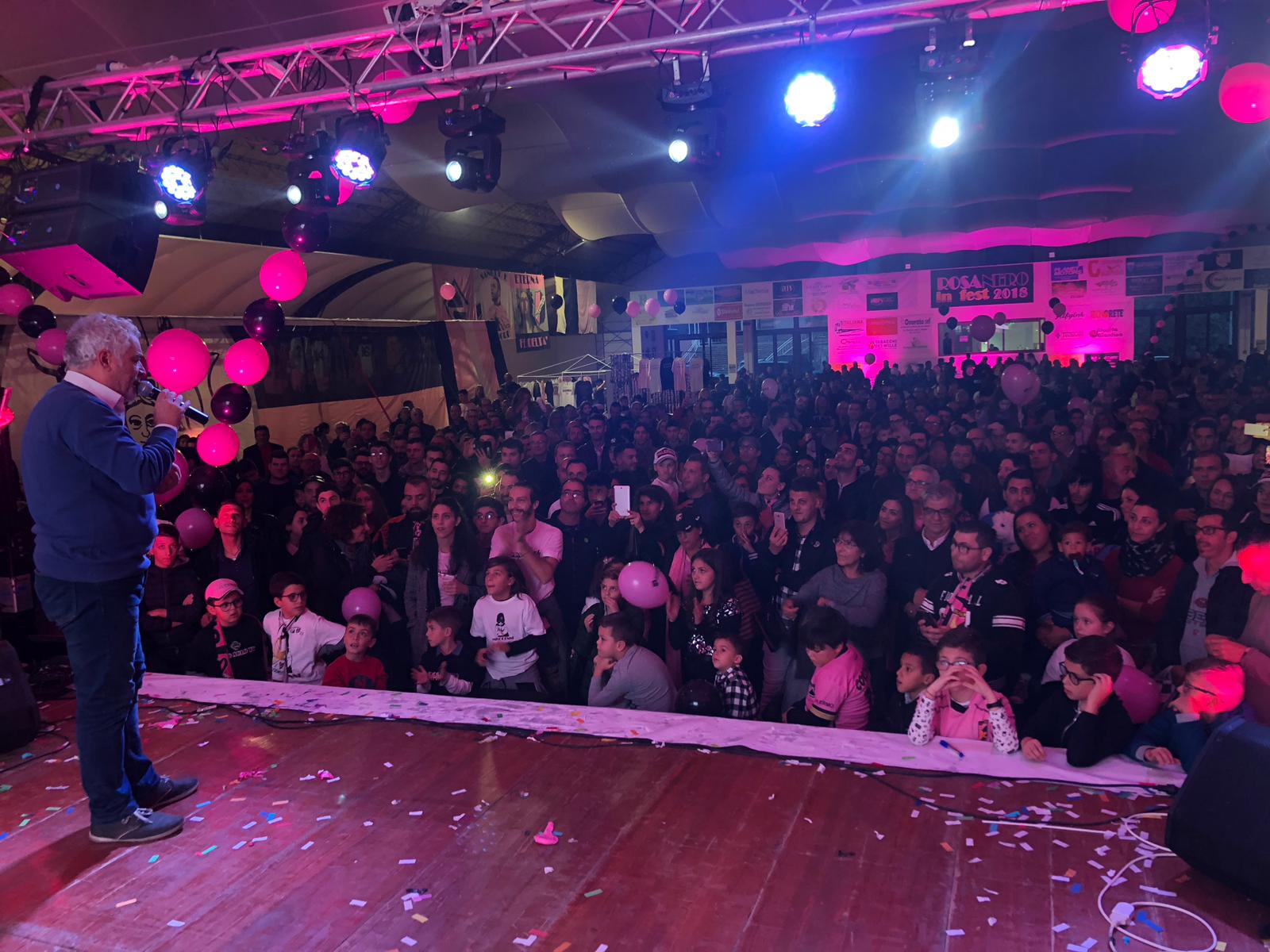 rosanero-in-fest-domenica-2018-2 Prosegue il programma di Rosanero in Fest, la festa dei colori rosanero e nella giornata di domenica, arriva uno dei momenti più sentiti e toccanti: sul palco sale Tony Sperandeo, per salutare il popolo rosanero, ma anche e soprattutto per il ricordo commosso di Gigi Burruano, scomparso un anno fa, tra storie e aneddoti legati al tifo per il Palermo LE FOTO DI ROSANERO IN FEST: LA VISITA DEI GIOCATORI Un momento toccante a cui Sperandeo aggiunge alla fine un appello a tutti i tifosi rosanero: “Dobbiamo andare allo stadio, dobbiamo andare allo stadio… dobbiamo andare allo stadio! Giocare con
